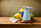 Still life ith lemons and blue enamel jug on wooden table