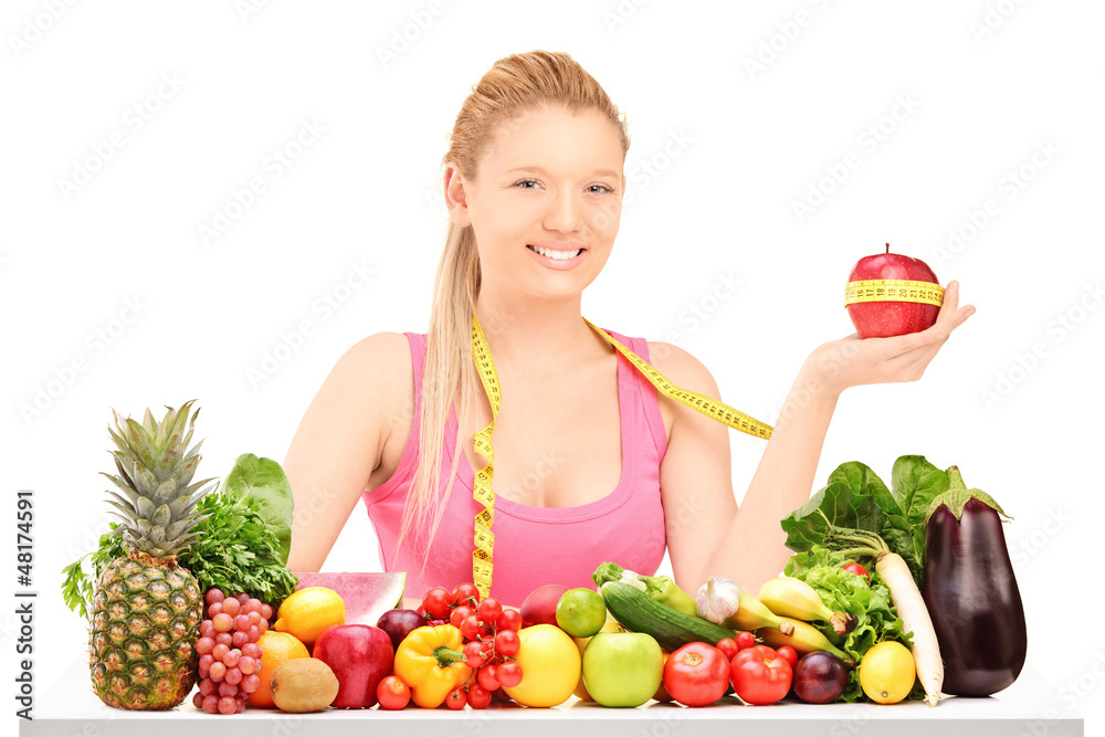 Female holding an apple wrapped with measuring tape on a table Female holding an apple wrapped with measuring tape on a table