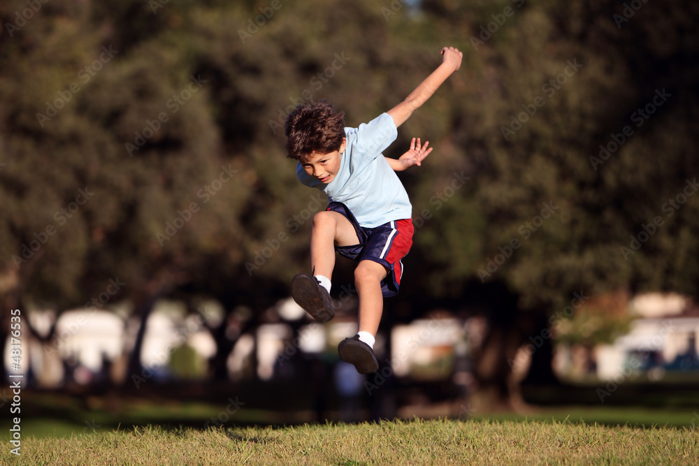 Happy young boy jumping and playing in the park Happy young boy jumping and playing in the park