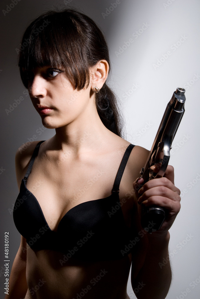 Sexy woman holding gun on gray