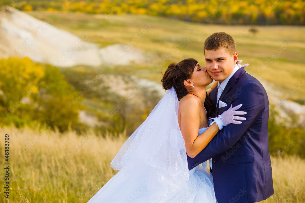 bride and groom outdoor standing in a yellow field hug, portrait