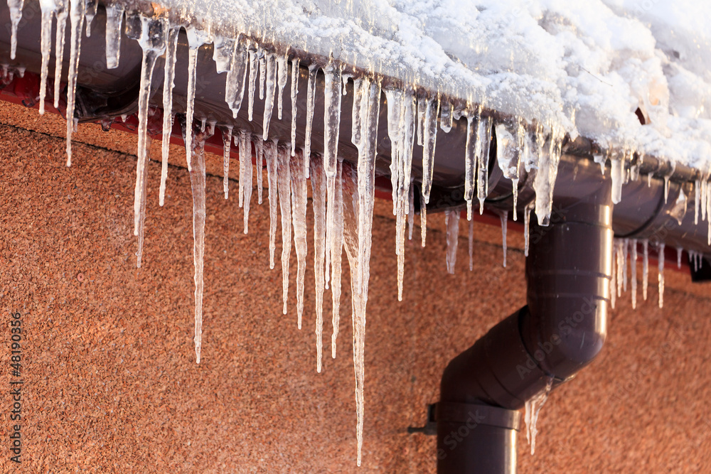 Naklejka premium Winter icicles hanging from eaves of roof