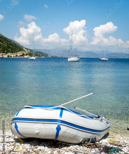 фотографія A dingy pulled up on a beach in paradise, from a nearby yacht