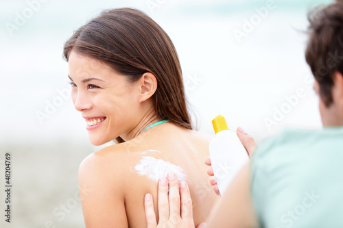 Suntan lotion /  Sunscreen - young couple on beach