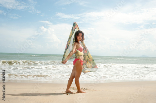 Pretty Asian woman on the beach with joy on her fabric .