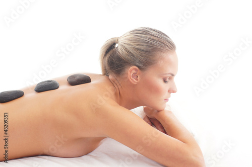 A young blond woman laying on a lava stone massage