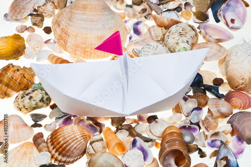 paper boat on background from sea shells photo