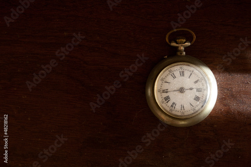 Dusty old pocket watch on wooden surface.