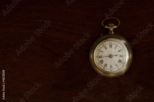 Dusty old pocket watch on wooden surface.