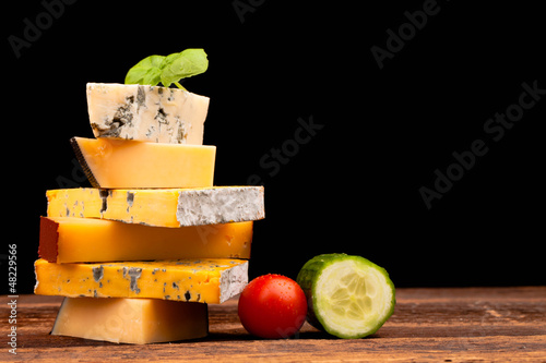 Various types of cheese and vegetables isolated on black
