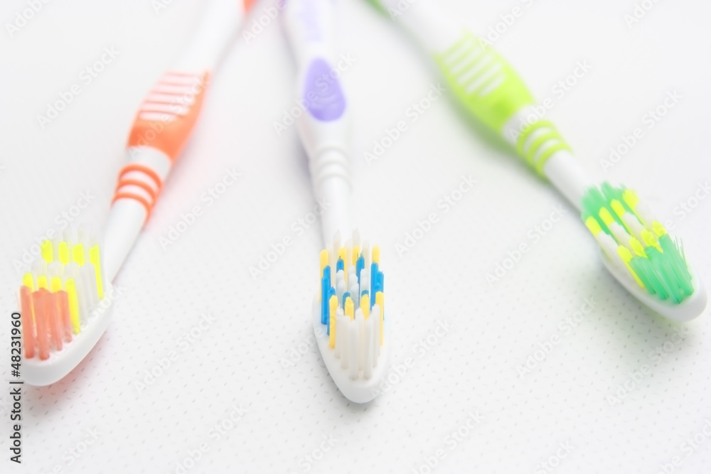 Closeup of three toothbrushes of different colors on the shelf. Closeup of three toothbrushes of different colors on the shelf.