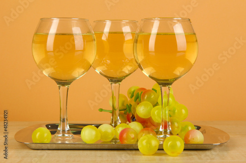 White wine in glass on salver on beige background