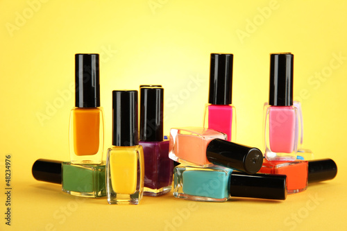Group of bright nail polishes, on yellow background © Africa Studio