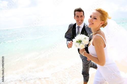 Just married couple running on a sandy beach photo