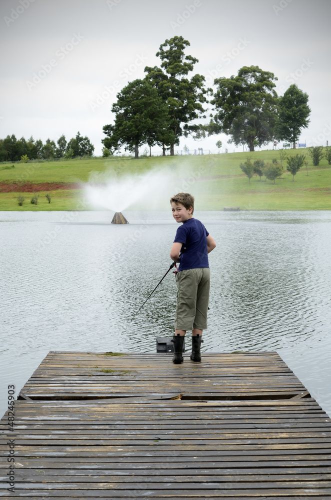 Boy bass fishing on dam or lake pier