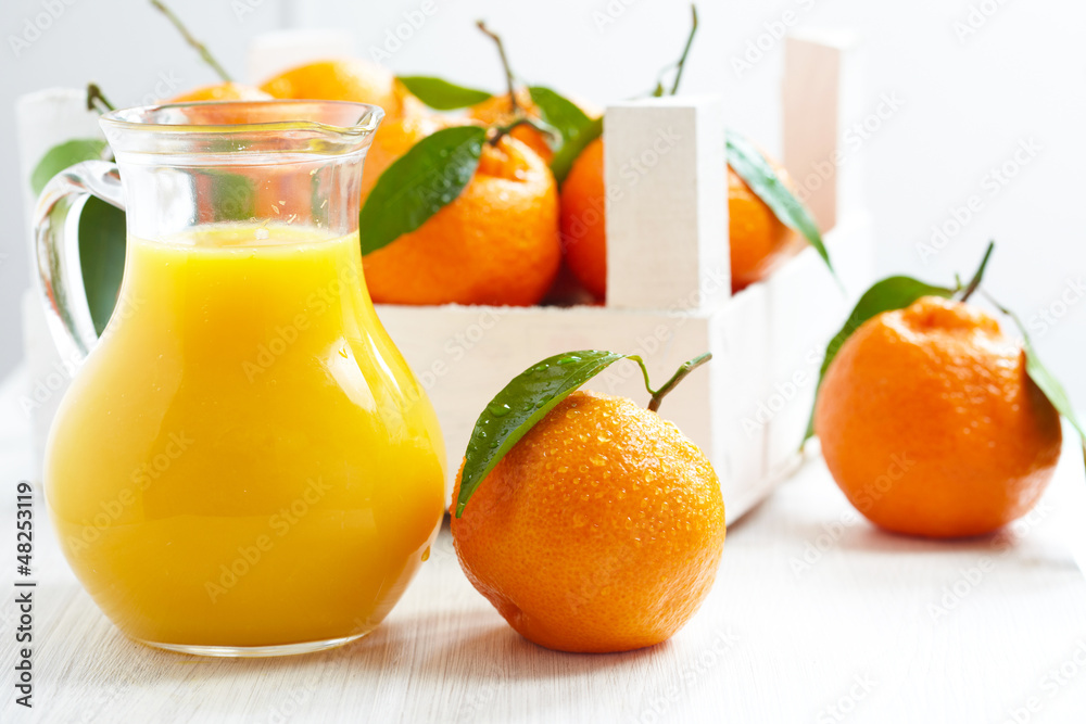 Orange juice in pitcher and tangerines