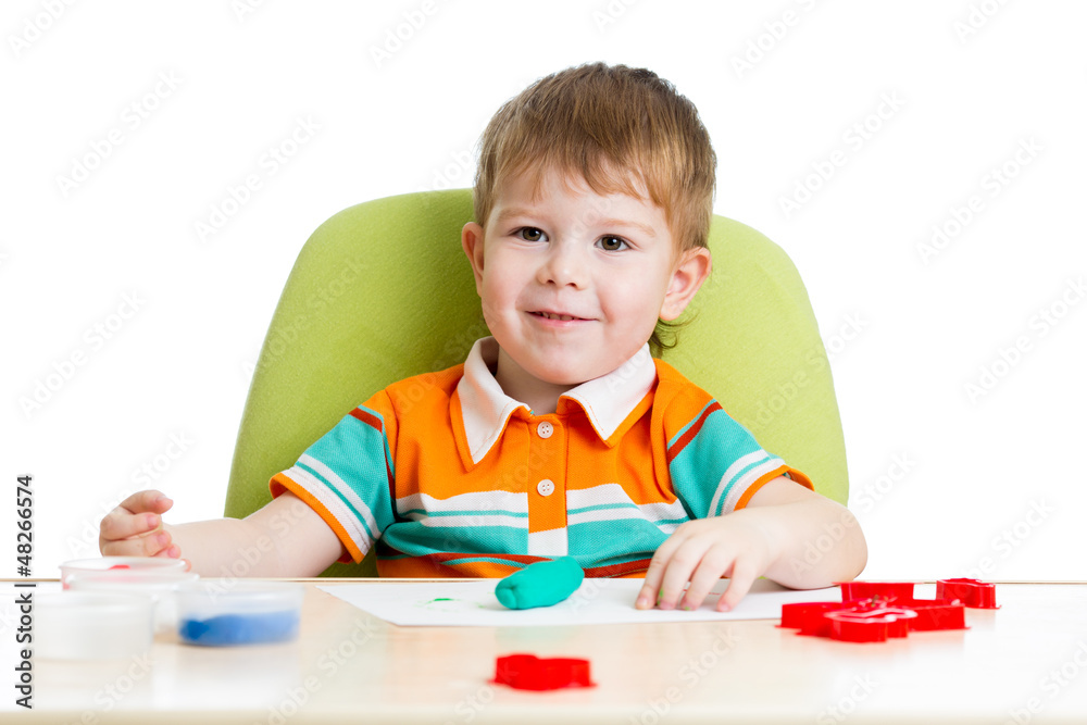 Happy little kid sitting at table and playing with colorful clay Happy little kid sitting at table and playing with colorful clay