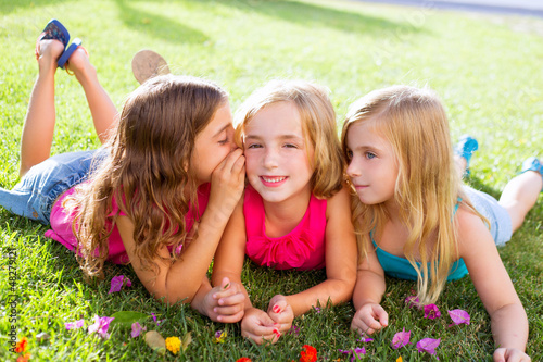 children girls playing whispering on flowers grass photo