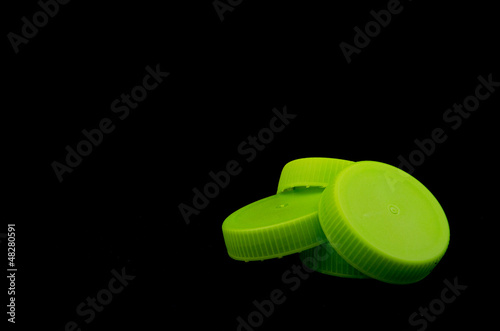 Pile of Green Bottle Caps on Black Background