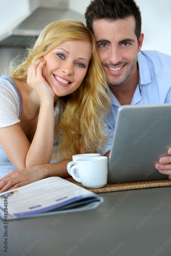 Young couple websurfing with tablet in home kitchen Young couple websurfing with tablet in home kitchen
