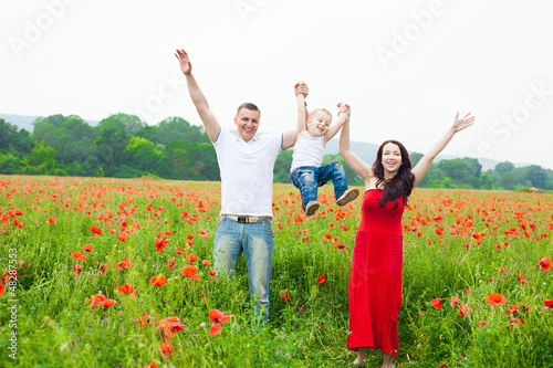 Happy family walking in poppy field