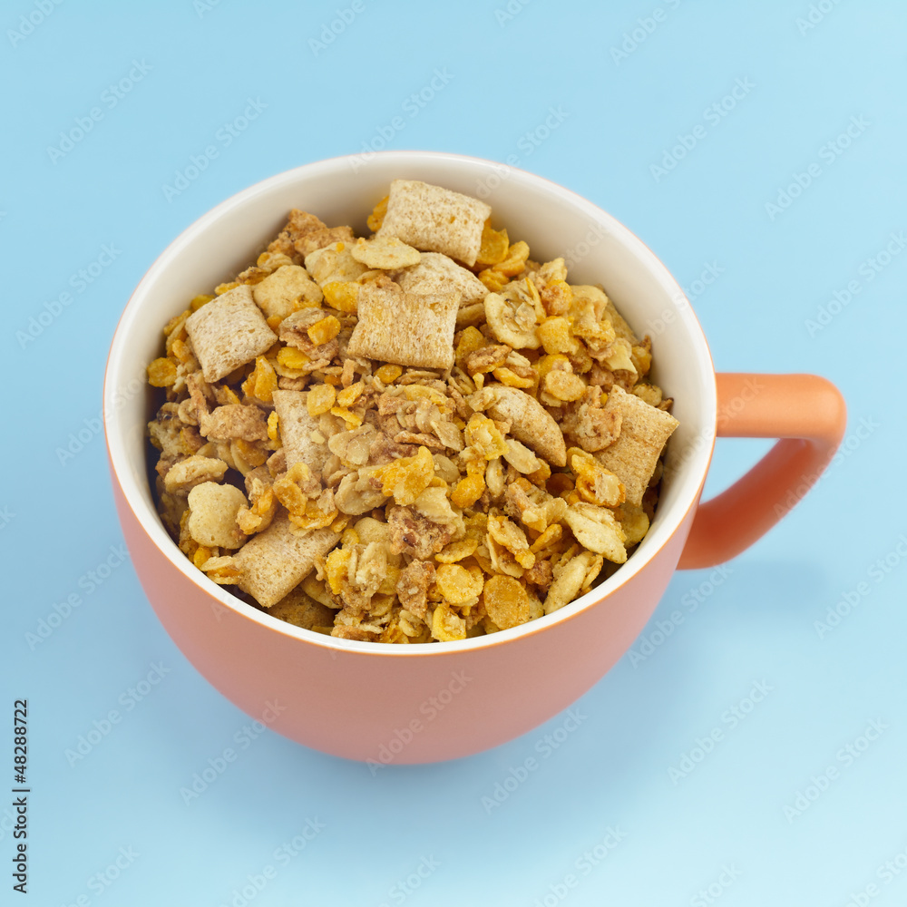 Orange Mug full of cereals on light blue background. Orange Mug full of cereals on light blue background.