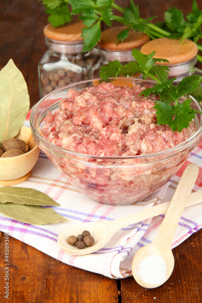 Bowl of raw ground meat with spices on wooden table Bowl of raw ground meat with spices on wooden table