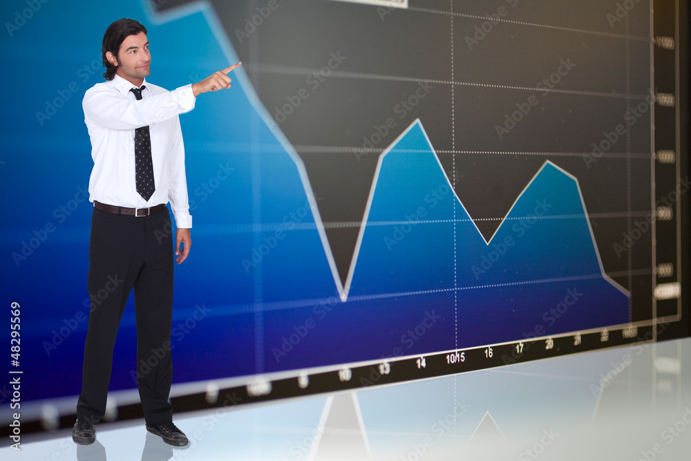 tall dark-haired man standing before graph tall dark-haired man standing before graph