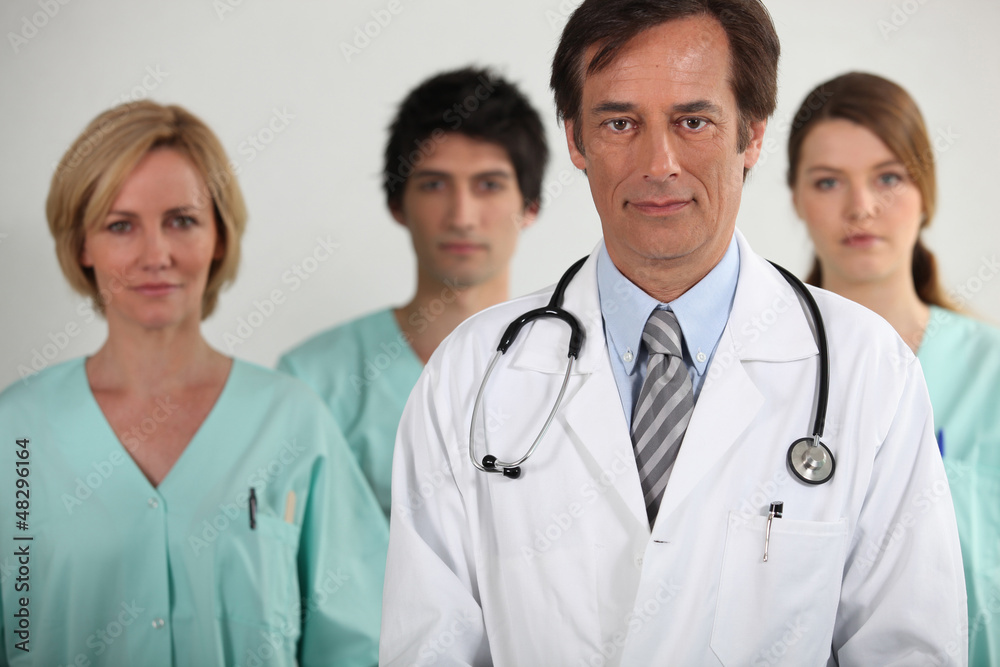 A doctor and three nurses behind him, all looking at us. A doctor and three nurses behind him, all looking at us.
