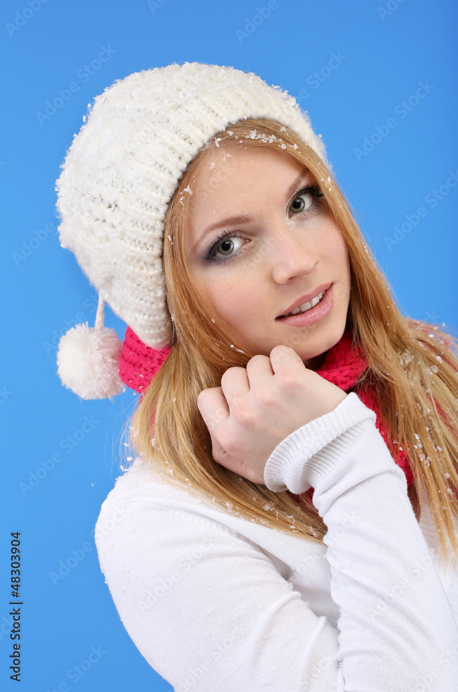 Young beautiful woman with snow on blue background