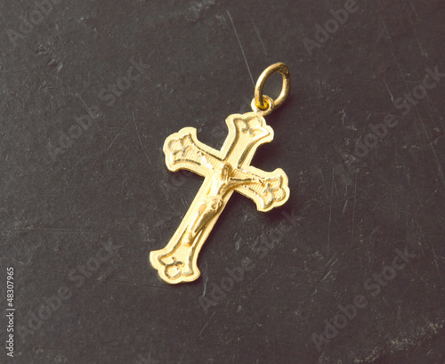 beautiful golden cross pendant on black stone background © venusangel