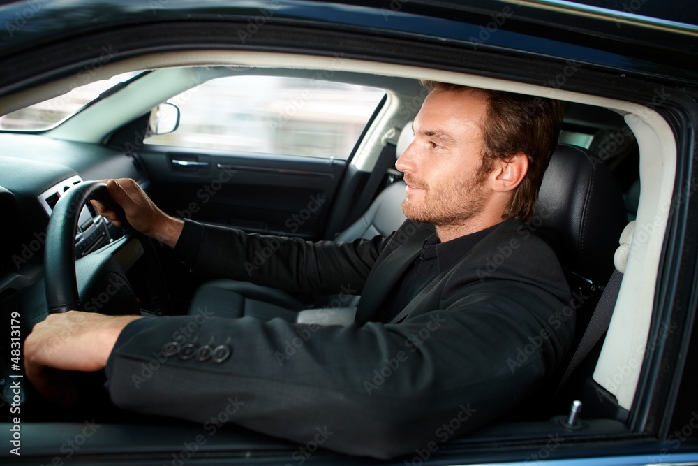 Young man driving luxury car smiling