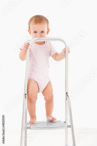 Impish little girl standing on top of ladder
