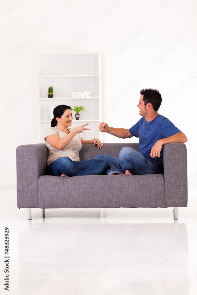 young couple playing rock-paper-scissors game at home