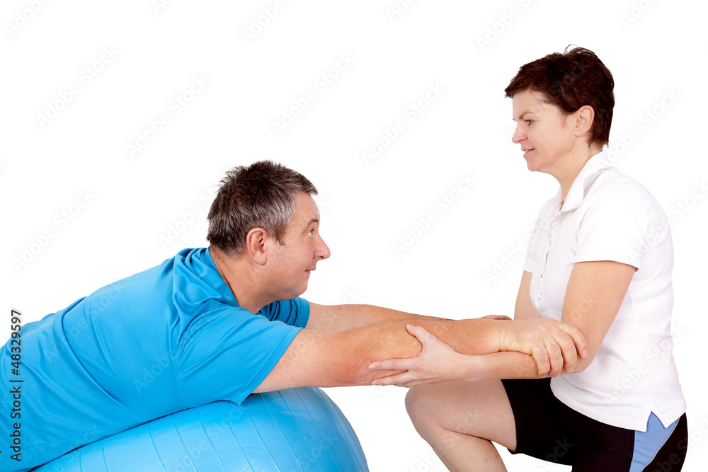 Woman helps man when practicing with the exercise ball Woman helps man when practicing with the exercise ball
