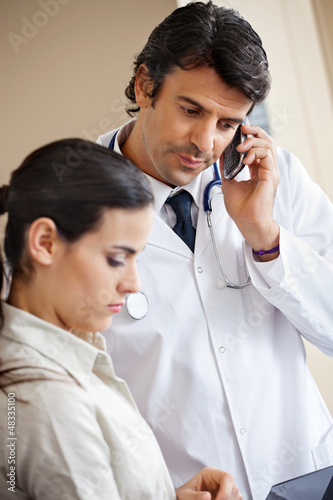 Doctor Attending Call While Standing With Colleague