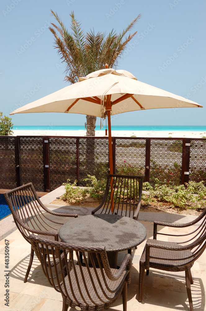 Chairs and umbrella near swimming pool by a beach of the luxury