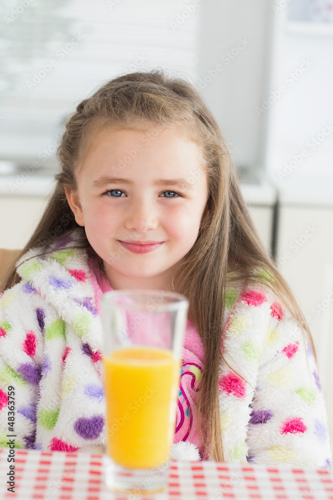 Little girl sitting while smiling with glass of orange juice Little girl sitting while smiling with glass of orange juice