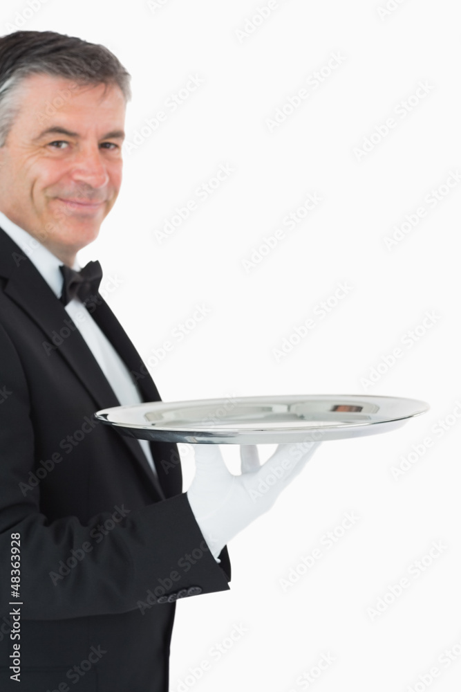 Waiter looking at camera while holding a silver tray Waiter looking at camera while holding a silver tray