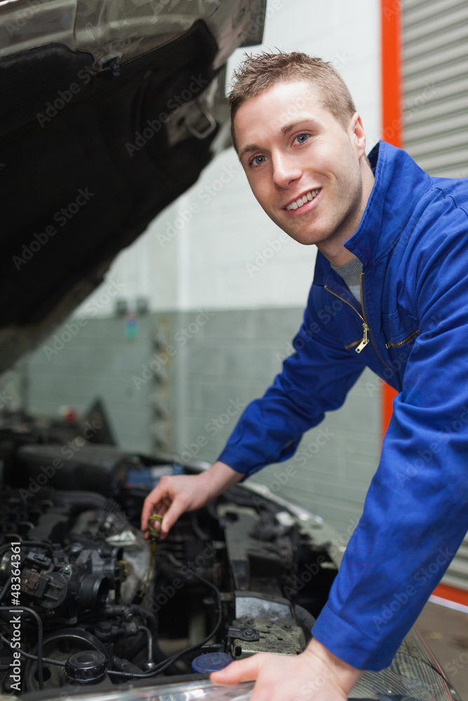 Auto mechanic checking car engine oil