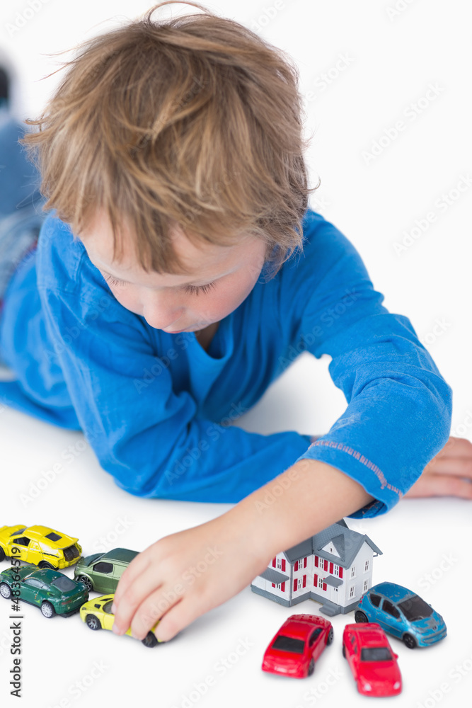 Close up of boy playing with playhouse and toy cars Stock Photo