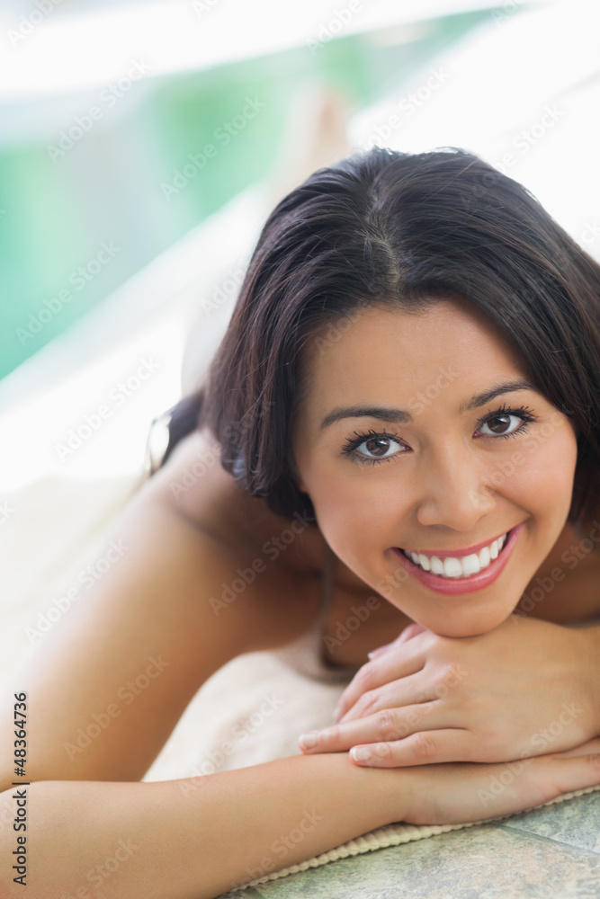 Woman lying on towel by pool Woman lying on towel by pool