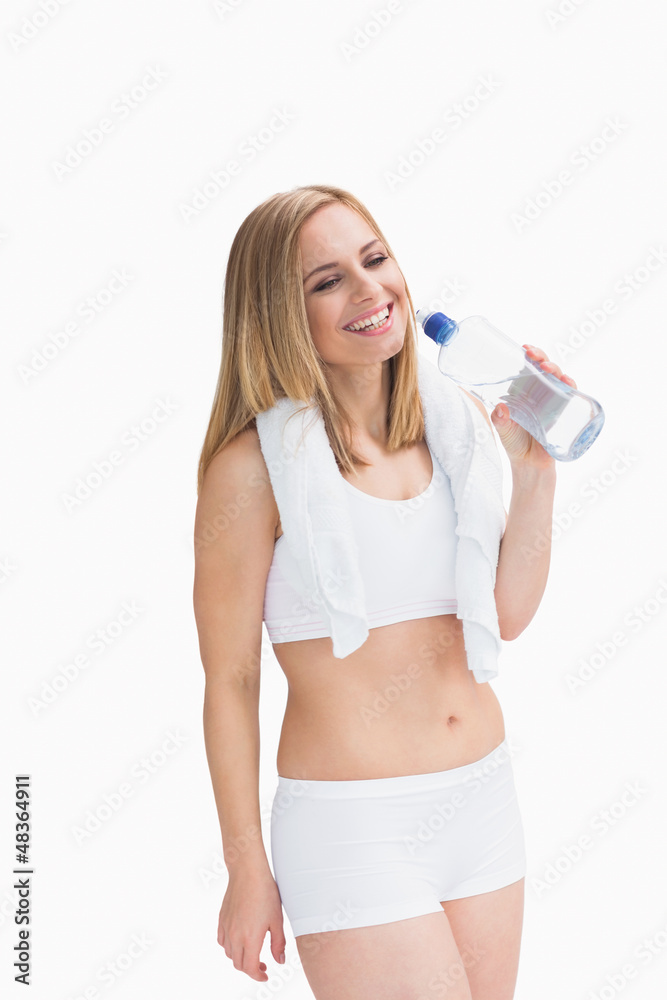 Happy young woman with towel around neck holding water bottle Happy young woman with towel around neck holding water bottle