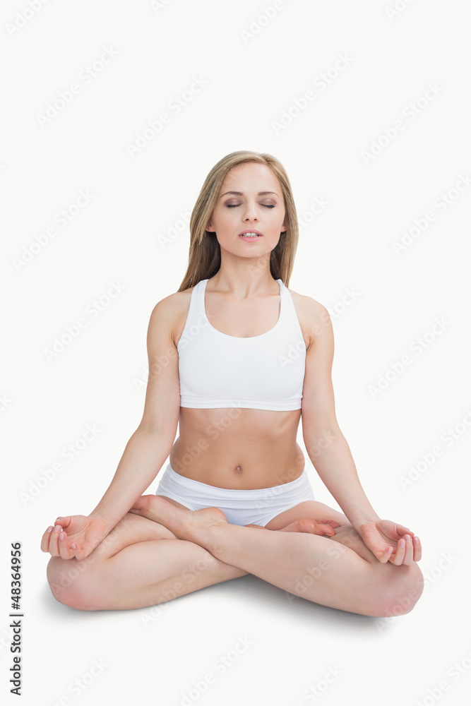 Woman sitting in lotus position with eyes closed Woman sitting in lotus position with eyes closed