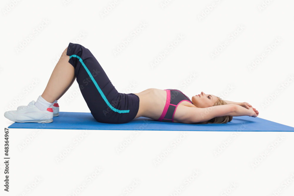Side view of woman in sportswear lying on yoga mat