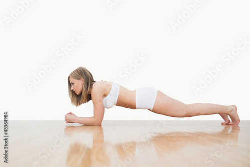 Side view of woman doing push-ups on hardwood floor