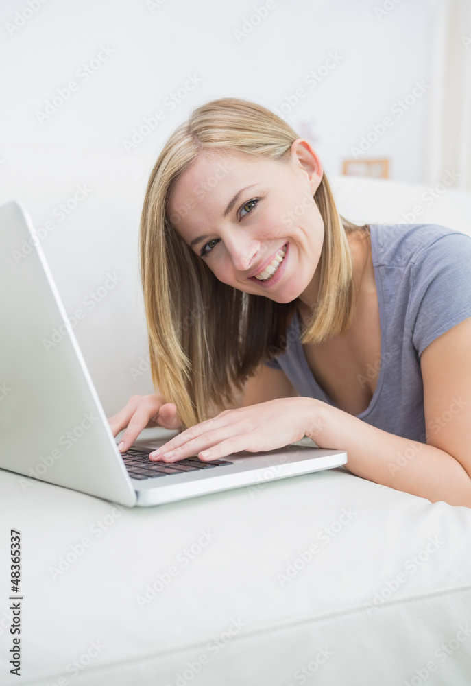 Portrait of casual woman lying on couch and using laptop Portrait of casual woman lying on couch and using laptop