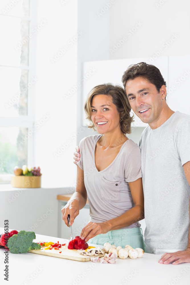 Smiling wife chopping vegetables with husband Smiling wife chopping vegetables with husband