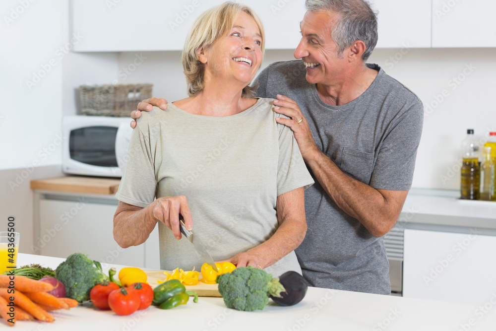 Smiling couple cutting vegetables together Smiling couple cutting vegetables together
