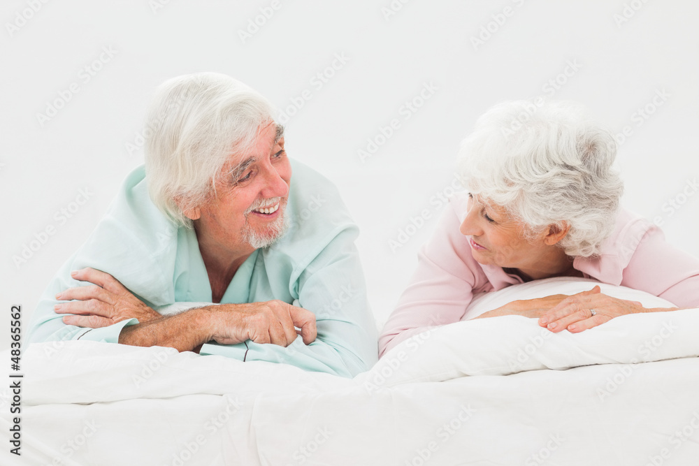 Happy couple looking at each other in bed